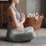 a pregnant woman wearing gray tank top meditating